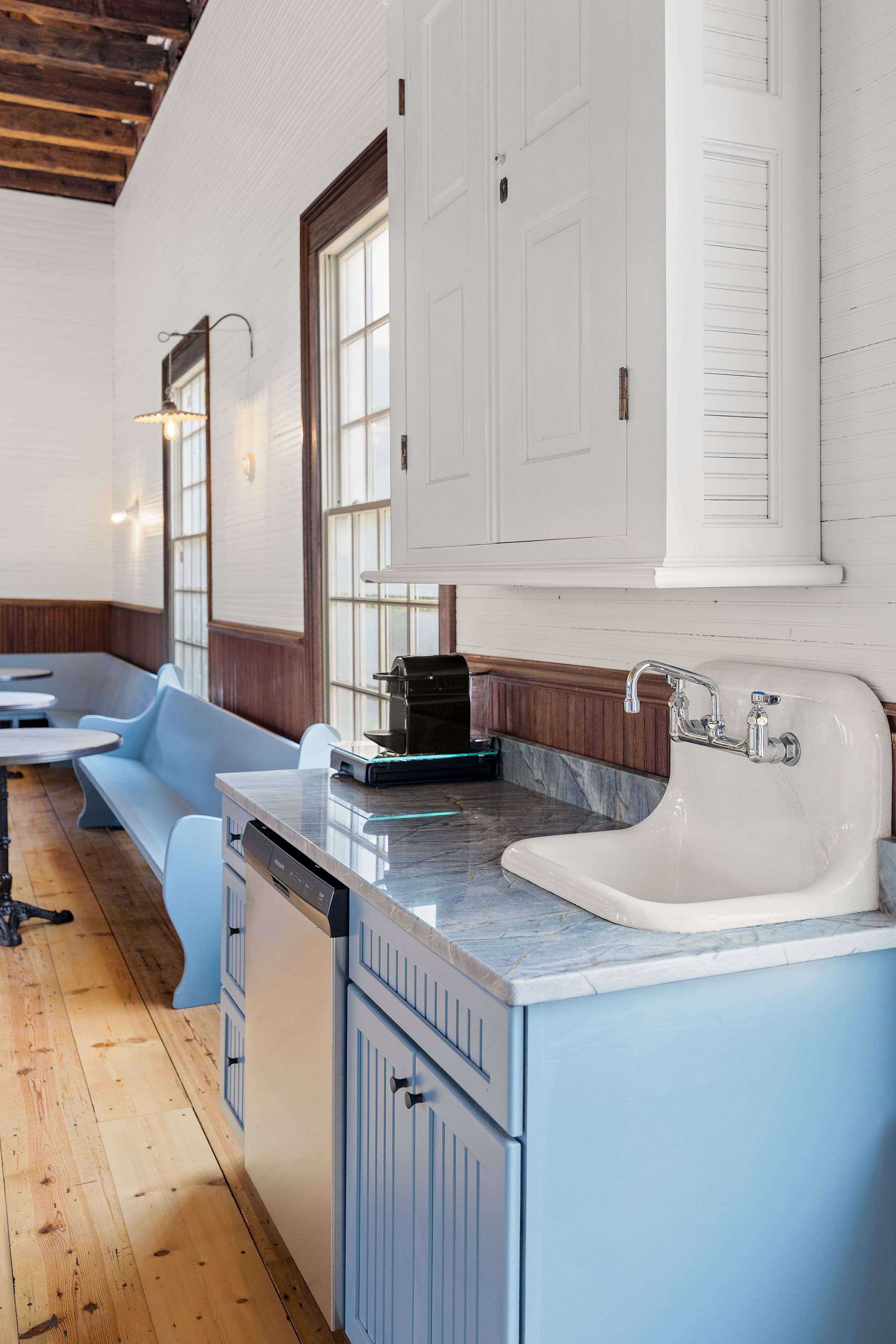 A modern kitchen corner featuring blue cabinetry, a marble countertop, a sink, and a coffee machine.