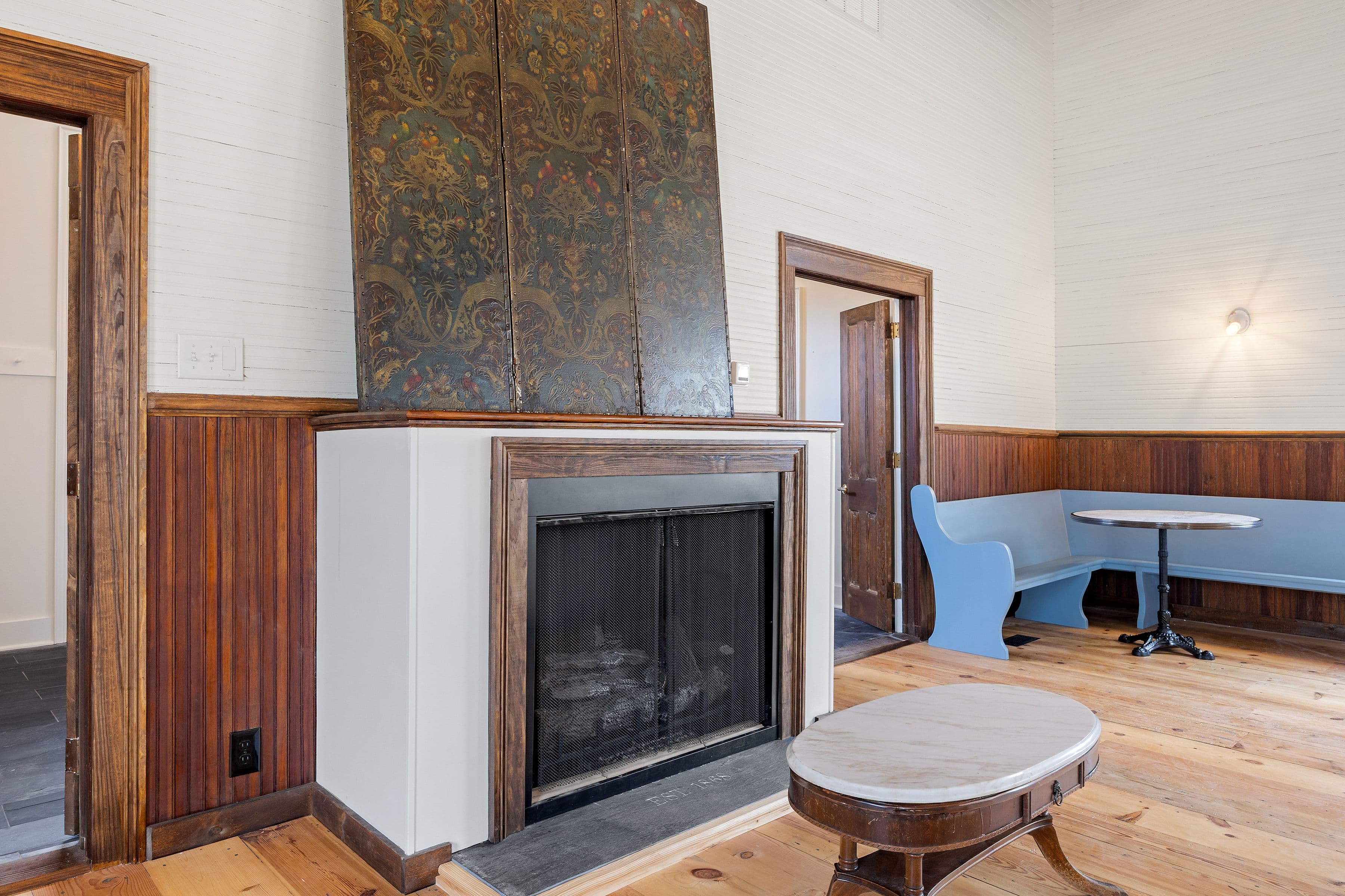A cozy room featuring a decorative fireplace, wooden walls, and a blue seating area.