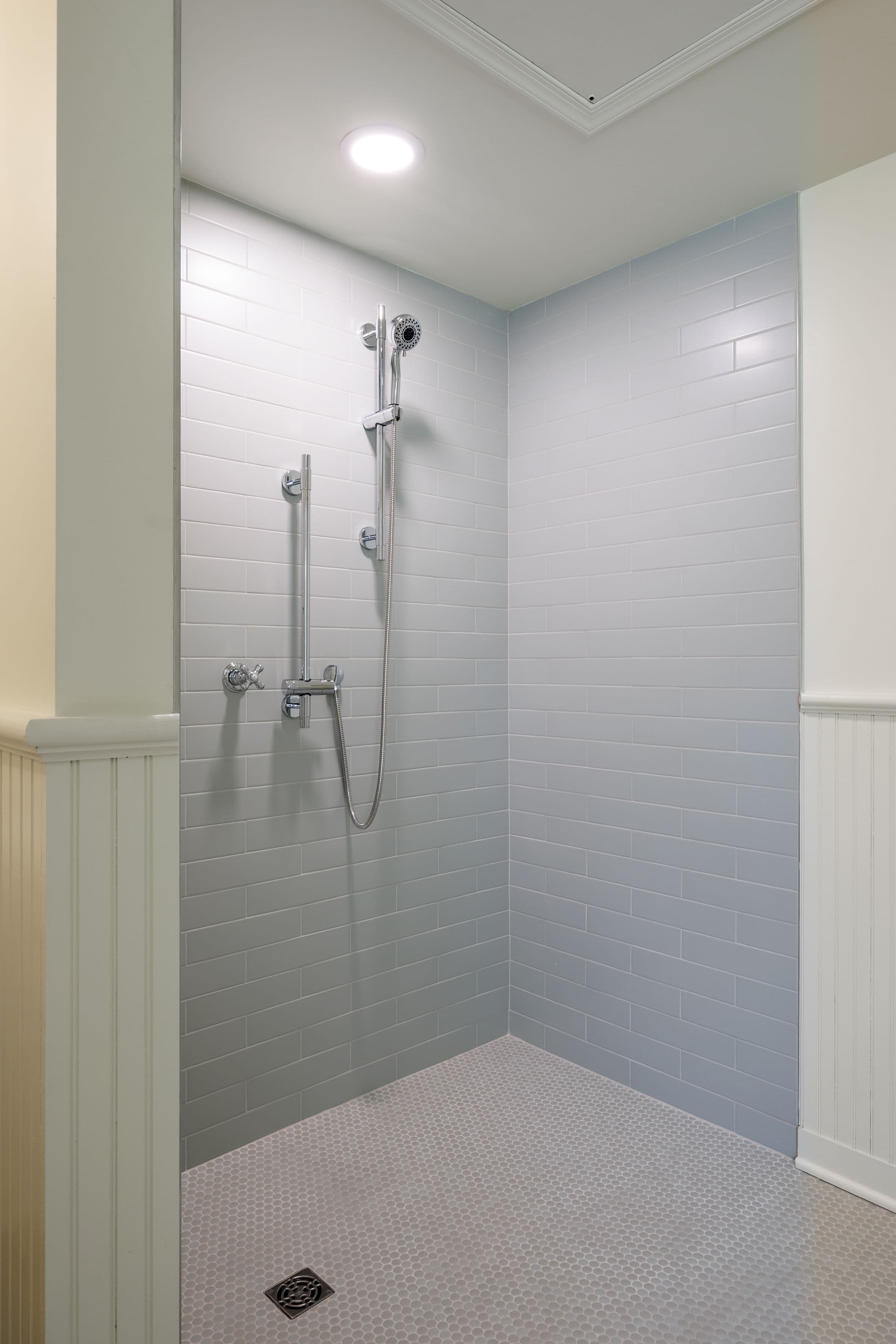Modern shower with light gray tile walls and a hexagonal floor.