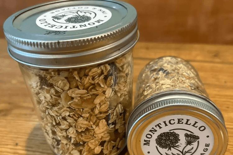 Two glass jars filled with granola and oats, featuring decorative labels, on a wooden surface.